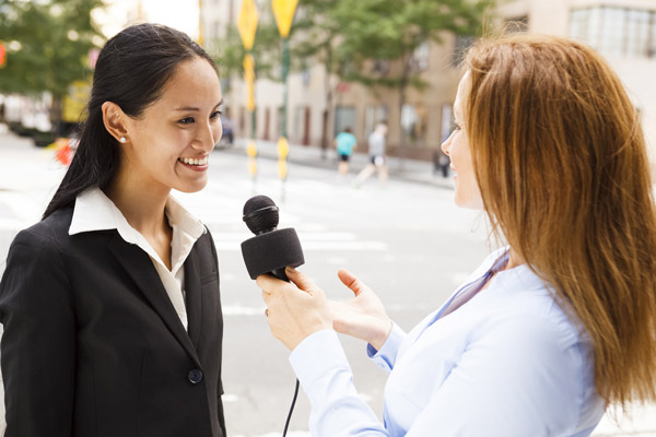 زن خبرنگار در حال مصاحبه با یک زن دیگر با میکرفن خبرنگاری